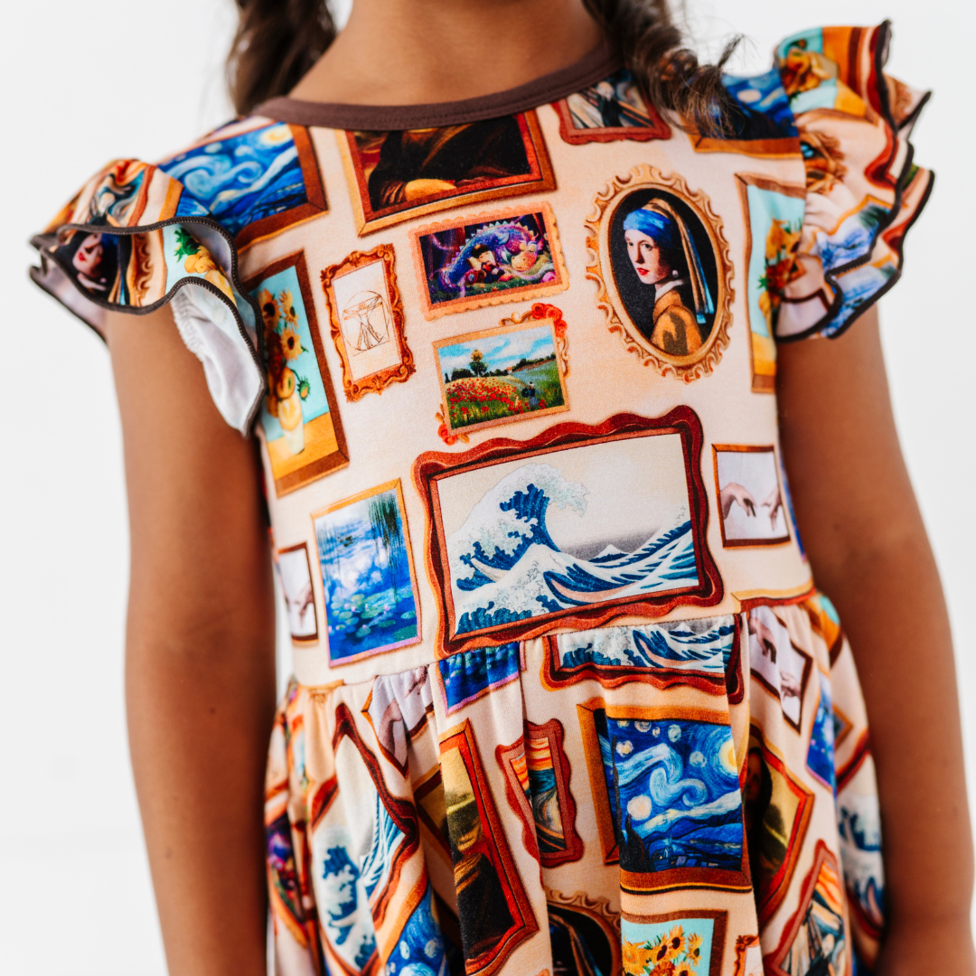 Close-up of a flutter-sleeve dress with a framed classic paintings print, ruffled shoulders, and brown neckline trim.